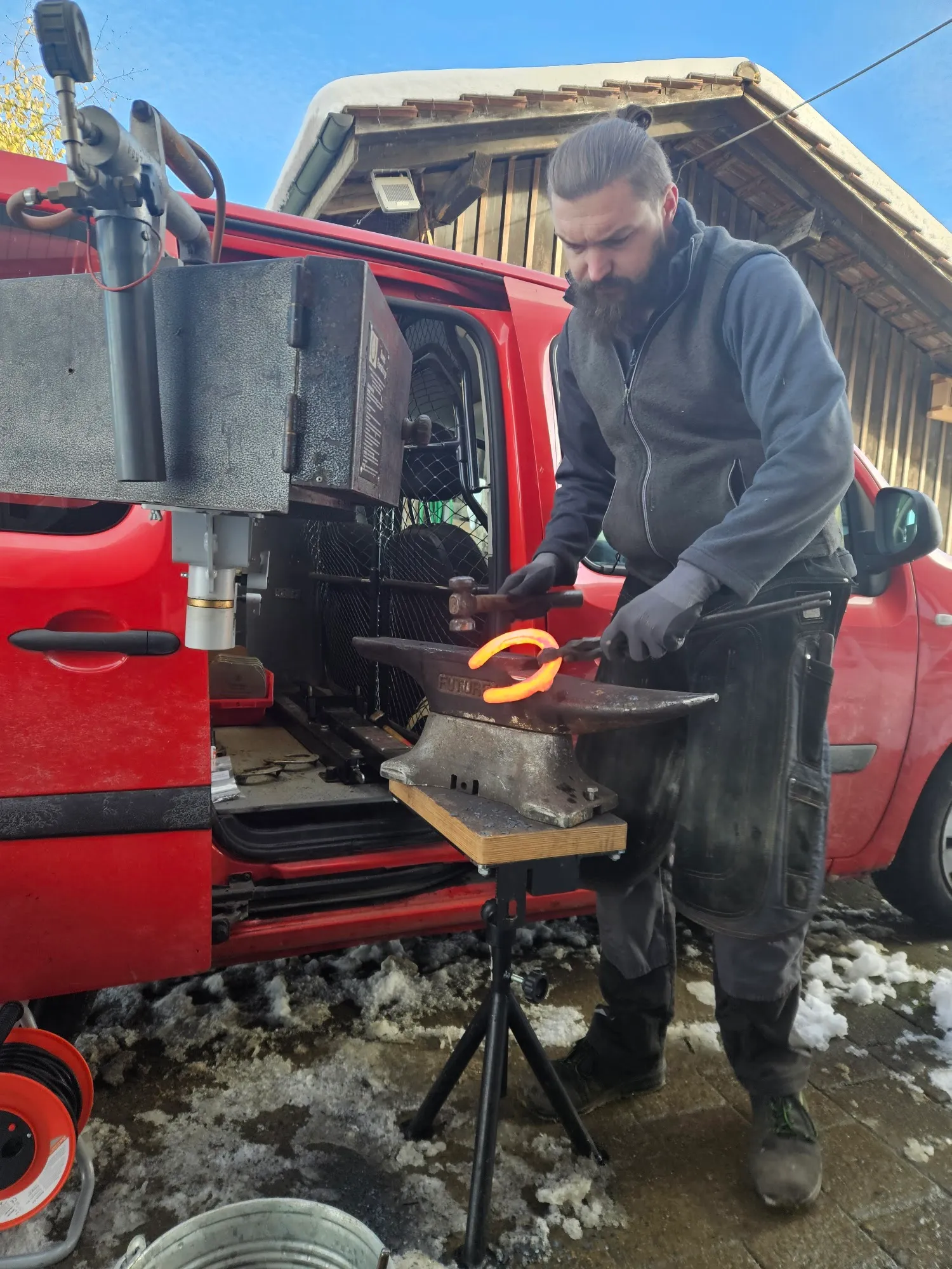 Juraj Hodas schmiedet ein glühendes Hufeisen am Amboss vor dem Werkstattbus